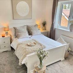 a white bed sitting in a bedroom next to a window