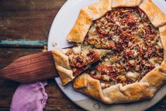 a pizza on a white plate with a wooden spatula next to it and a purple napkin