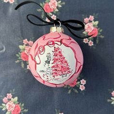 a pink christmas ornament with a drawing of a woman and dog on it