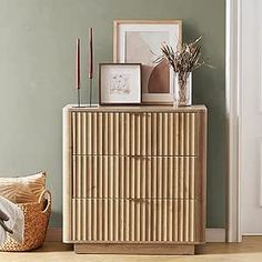 a wooden cabinet sitting next to a wall with pictures on it and candles in front of it