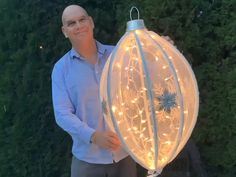 a man is holding a large light up birdcage