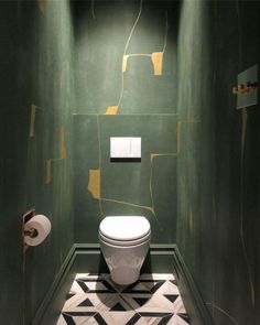 a white toilet sitting in a bathroom next to a green wall