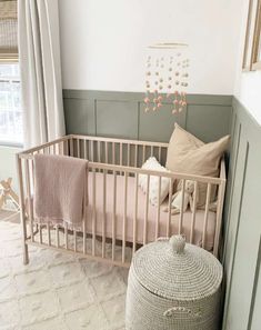 a baby crib with pink and white bedding next to a window in a bedroom