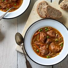 two bowls of soup with bread on the side