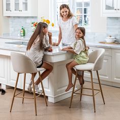 three children sitting at the kitchen counter with their mother and sister in front of them