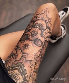 a woman's leg with tattoos and flowers on it