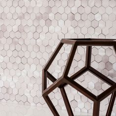 a black vase sitting on top of a white table next to a wall covered in hexagonal tiles