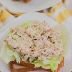 two white plates topped with sandwiches covered in lettuce