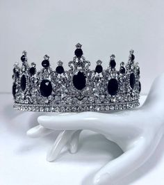 a white mannequin holding a silver and black tiara