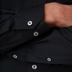 The James solid OoohCotton shirt features a point collar, adjustable notched cuffs, mother-of-pearl buttons, and a curved hem perfect for wearing tucked or untucked. OoohCotton is a performance, double-mercerized, wrinkle-resistant, breathable, and easy-care cotton blend with 8-way stretch, quick-dry, and thermal comfort properties. Solid Color Collared Shirt With Functional Buttons, Timeless Long Sleeve Dress Shirt With Button Cuffs, Black Spread Collar Top With Hidden Button Closure, Black Tops With Hidden Button Closure And Spread Collar, Black Long Sleeve Tops With Hidden Button Closure, Black Collared Top For Semi-formal Occasions, Black Long Sleeve Top With Hidden Button Closure, Black Semi-formal Top With Fold Down Collar, Black Shirt With Fold Down Collar