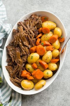 a bowl filled with meat, potatoes and carrots on top of a blue and white towel