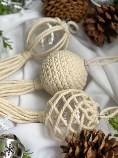 some white balls and pine cones are sitting on a table with twine wrapped around them