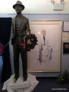 a statue of a man holding a wreath next to a drawing of a man in a suit and tie