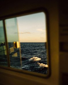 the reflection of an ocean view through a window on a boat in the water at sunset