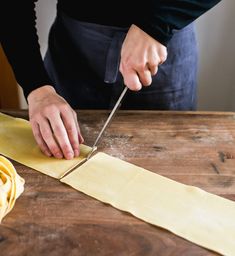 a person cutting up some food on top of a wooden table