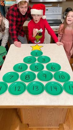 a group of kids standing around a table with numbers on it and santa hats on