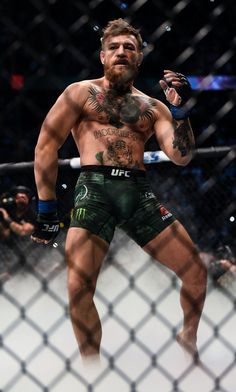 a man standing next to a fence holding a wrestling glove