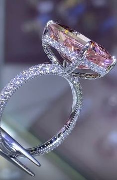 an engagement ring with a fancy pink diamond on it's side and two diamonds in the middle