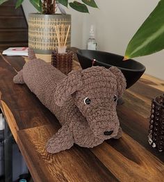 a stuffed dog laying on top of a wooden table next to a potted plant