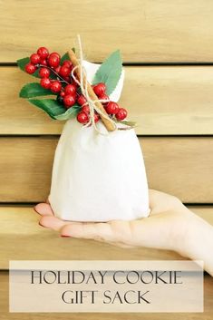 a hand holding a white bag with red berries on it and the words holiday cookie gift sack