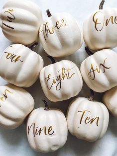 white pumpkins with gold writing on them are arranged in the shape of five words