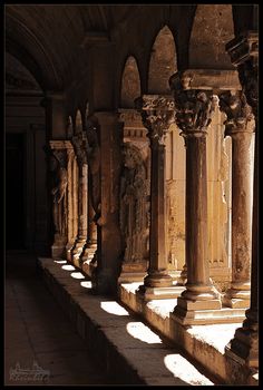 the sun is shining through the windows in an old building with stone columns and statues