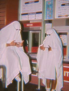 two people in white robes sitting at a vending machine with their hands on their hips