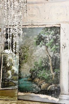 an old painting is hanging on the wall next to a window with beaded chandelier