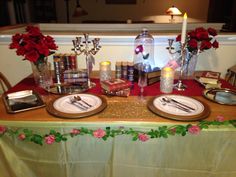 the table is set with plates and silverware, candles, books, and flowers