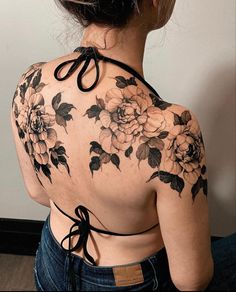 the back of a woman's shoulder with flowers on it and black laces