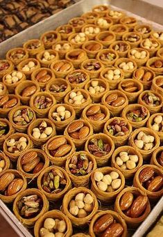 there are many different kinds of nuts in the trays on the table, including almonds and pistachios