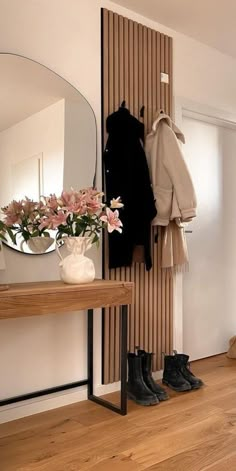 there is a coat rack with shoes and flowers on it in the corner next to a mirror