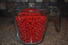 a glass measuring cup filled with red candy