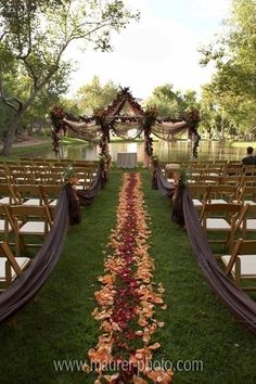 the aisle is lined up with flowers and greenery for an outdoor wedding ceremony in front of a lake