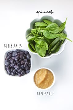 blueberries, applesauce and spinach in small bowls on a white surface