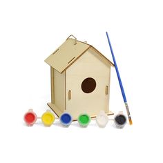 a wooden birdhouse with paint and brushes next to it