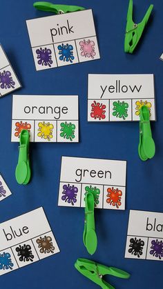 scissors and paper clips are on the table with name cards for orange, yellow, green