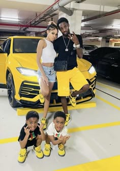 three kids posing in front of a yellow sports car with their mom and dad standing next to them