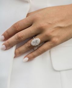 a close up of a person's hand with a ring on their finger, wearing a white dress