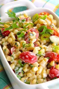 a white dish filled with corn and tomatoes