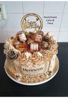 a birthday cake decorated with liquor bottles and gold trimmings on a black countertop