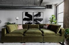 a large green couch sitting in a living room next to a tall painting on the wall