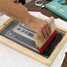 a man is using a wooden block to stamp something on a piece of wood with a rubber pad