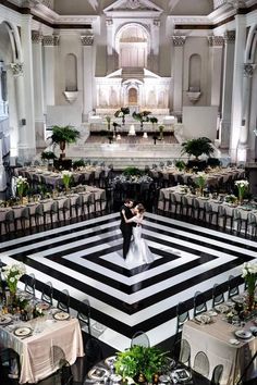 a bride and groom standing in the middle of a large room with tables set for dinner