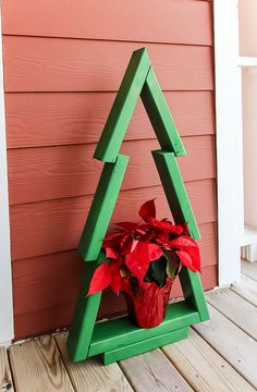 a christmas tree shaped planter with poinsettis in it on a porch