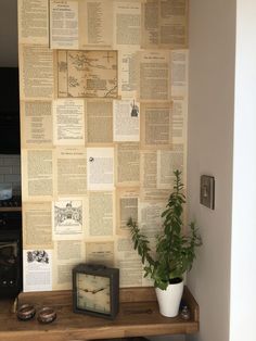 a table topped with a clock and a potted plant next to a wall covered in books