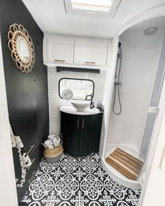 a bathroom with black and white tiles on the floor, sink and shower stall area