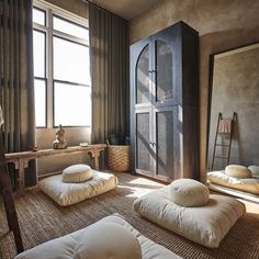 a living room with lots of pillows on the floor next to a tall cabinet and window