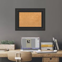 a desk with a laptop computer and a cork board on the wall above it, along with other office supplies