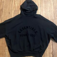 The Fear Of God Essentials Hoodie Provides Volume In The Body And Sleeves With The Intent Of Creating A Soft, Round, Cropped Silhouette. A Mock Neckline And Side Seam Pockets To Provid Fall Streetwear Funnel Neck Hoodie, Black Funnel Neck Sweatshirt For Streetwear, Fall Hooded Top With Logo Print, Logo Print Hoodie For Fall, Black Hoodie With Funnel Neck For Streetwear, Black Funnel Neck Sweatshirt With Drawstring Hood, Black Funnel Neck Casual Hoodie, Casual Black Sweatshirt With Funnel Neck, The Fear Of God